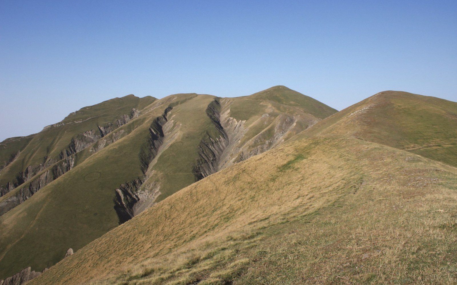 Grassy mountain ridge with steep eroded gullies cutting down one slope